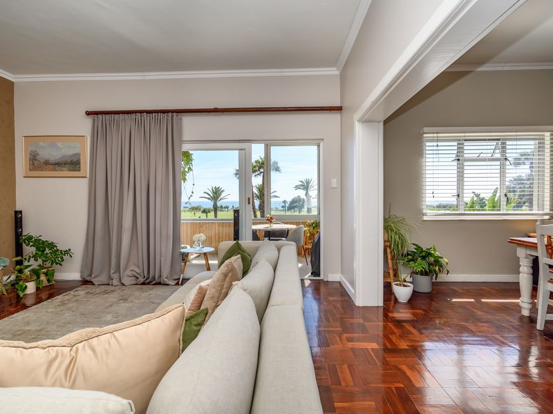 Spacious open-plan living and dining area featuring polished parquet flooring, crown molding, and large sliding doors leading to a balcony with scenic views.