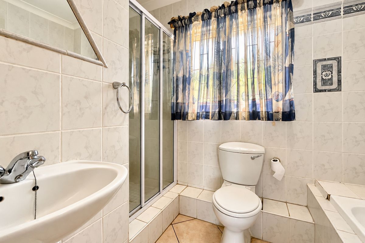 A functional bathroom featuring a pedestal basin, shower enclosure, toilet, and built-in bathtub with tiled finishes throughout.