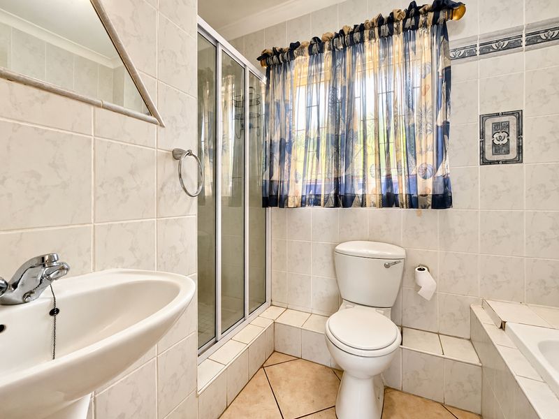 A functional bathroom featuring a pedestal basin, shower enclosure, toilet, and built-in bathtub with tiled finishes throughout.