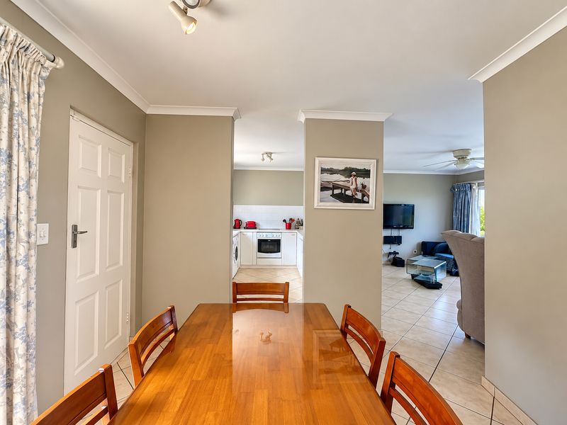 Open-plan living and dining area featuring tiled flooring, coved cornicing, and a functional kitchen with built-in cabinetry and appliances.