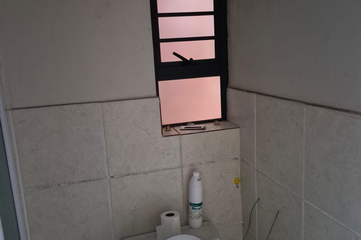 A small bathroom featuring tiled walls and a standard toilet, currently showing signs of wear and requiring maintenance to the wall finishes.