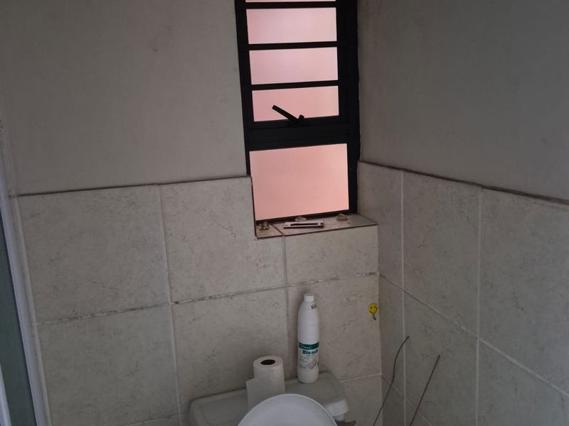A small bathroom featuring tiled walls and a standard toilet, currently showing signs of wear and requiring maintenance to the wall finishes.