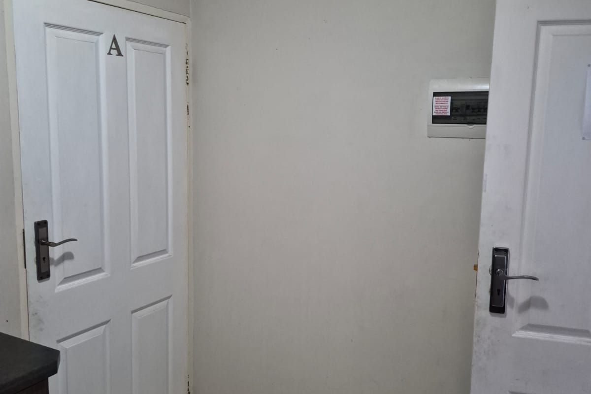 An entry area featuring tiled flooring, two panel doors, and a wall-mounted electrical distribution board.