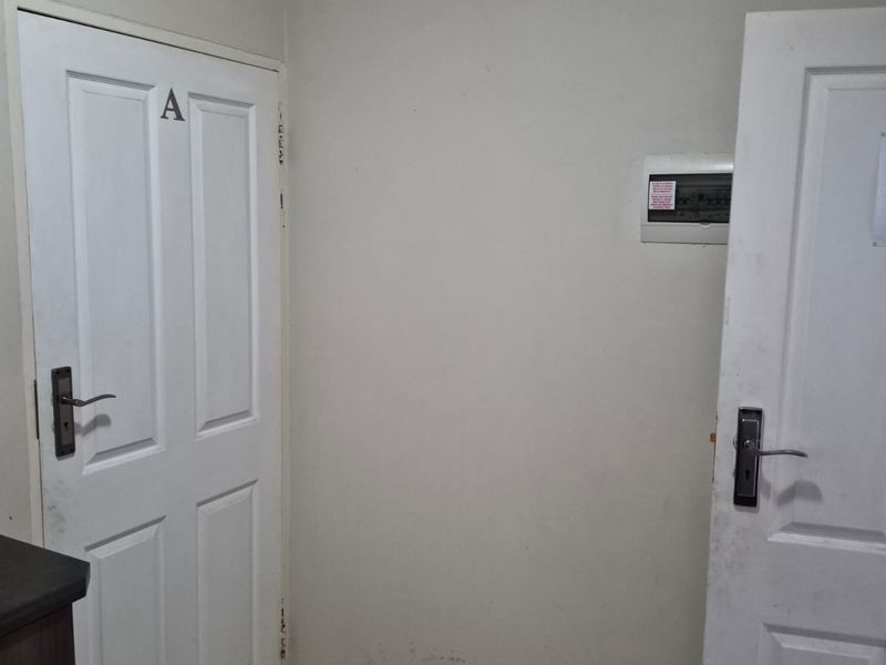An entry area featuring tiled flooring, two panel doors, and a wall-mounted electrical distribution board.