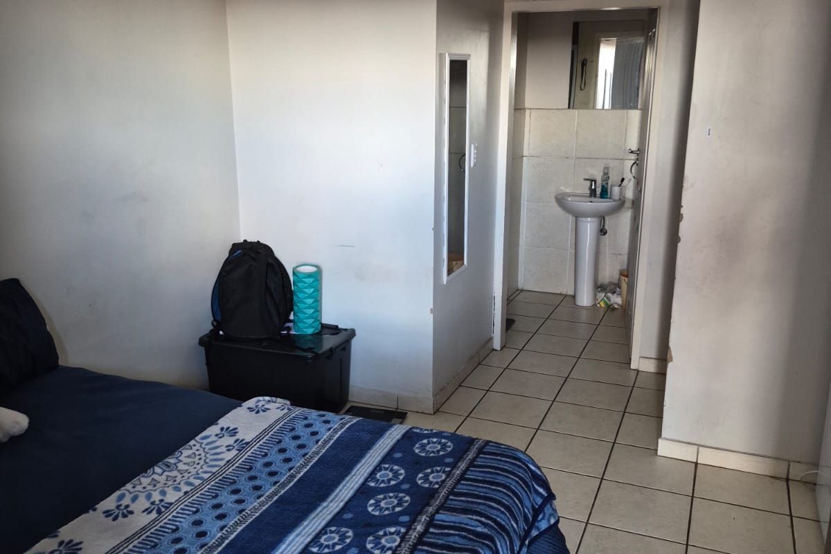 Bedroom featuring ceramic floor tiles and an adjoining en-suite bathroom with a pedestal basin.