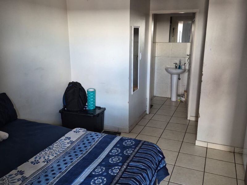 Bedroom featuring ceramic floor tiles and an adjoining en-suite bathroom with a pedestal basin.
