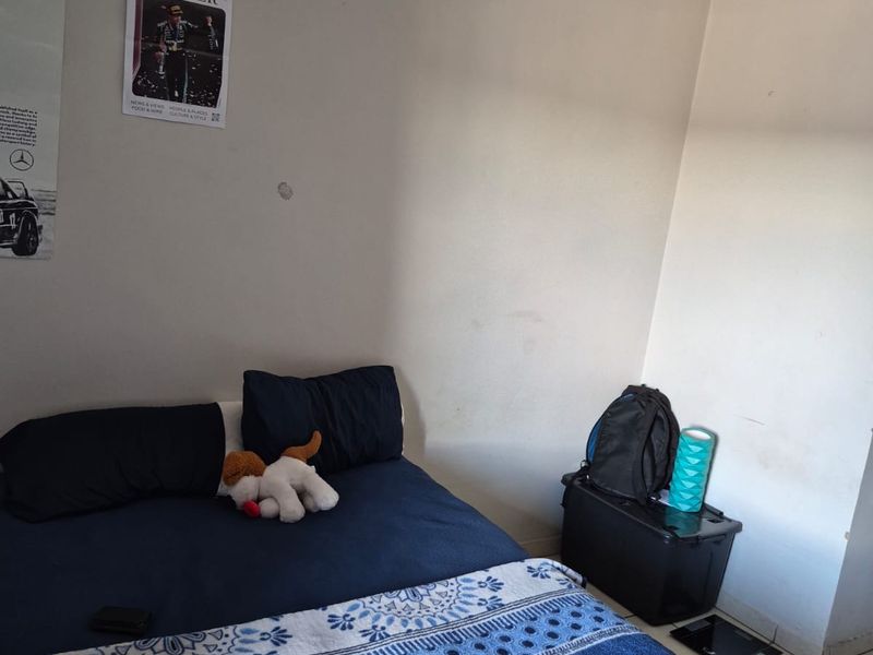 A bedroom featuring tiled flooring and coved ceiling details, currently requiring minor cosmetic wall repairs and fresh paint to enhance the space.