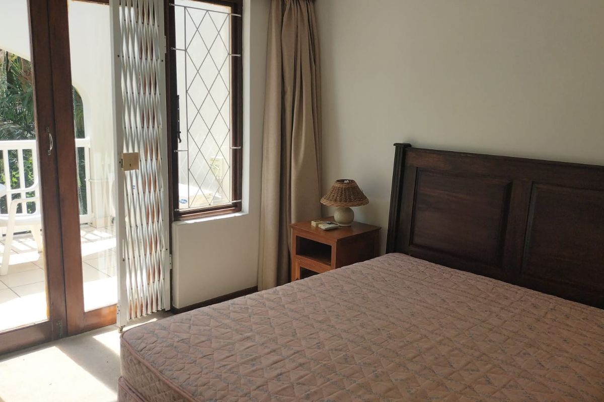 A bedroom featuring a sliding glass door with a security gate, providing direct access to an outdoor balcony area.