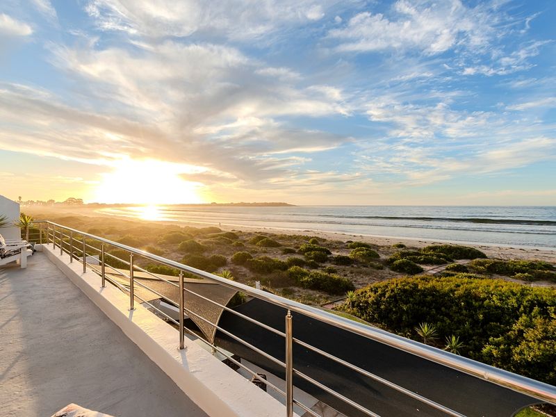 Elevated balcony offering expansive, unobstructed sunset views over the coastline, beach, and ocean.