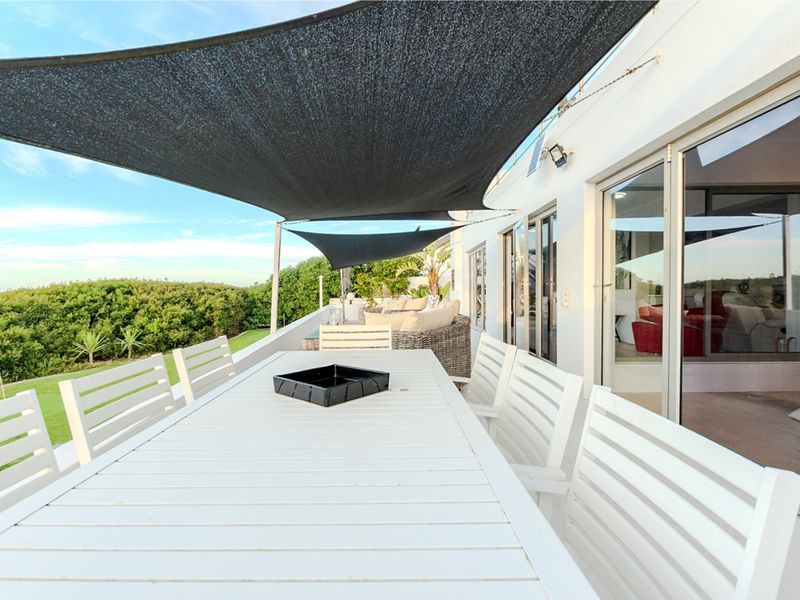 Spacious outdoor patio featuring a protective shade sail, tiled flooring, and seamless access to the interior living areas through large sliding glass doors.