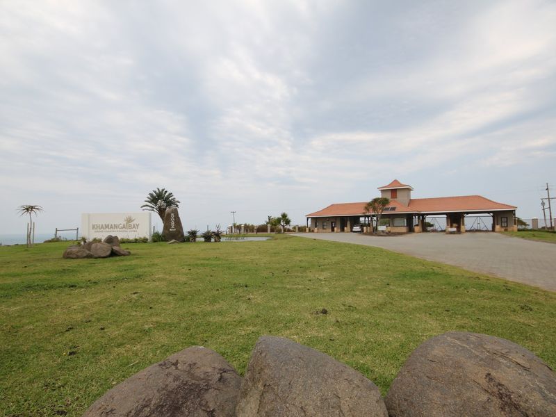 The entrance to Khamanga Bay estate featuring a paved driveway, security gatehouse, and well-maintained landscaped grounds.