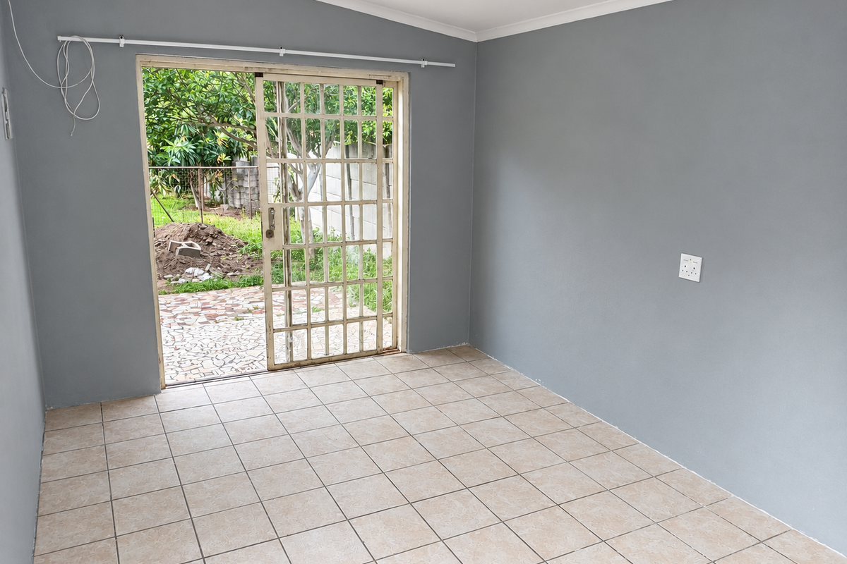 An empty living room featuring neutral grey walls, tiled flooring, and a sliding glass door with a security gate leading to the backyard.