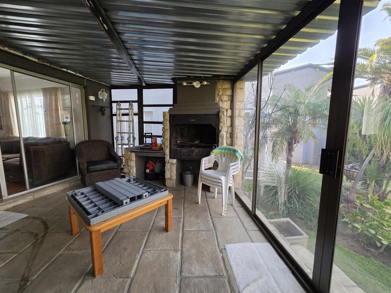 Enclosed patio area featuring a built-in braai, stone cladding, and sliding glass doors, providing a functional space for outdoor entertaining.