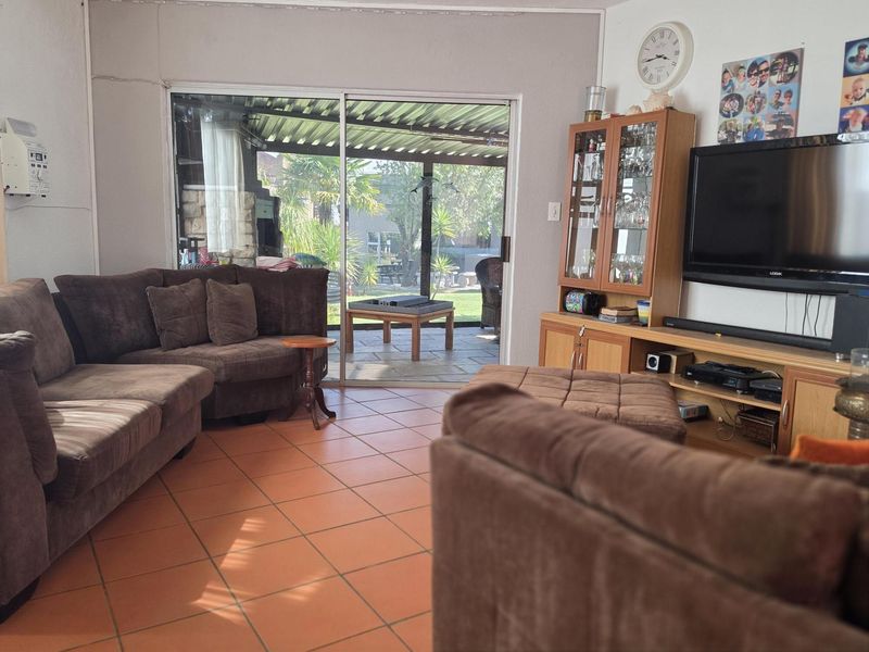 Spacious living room featuring terracotta floor tiles and large sliding glass doors providing direct access to a covered outdoor patio area.