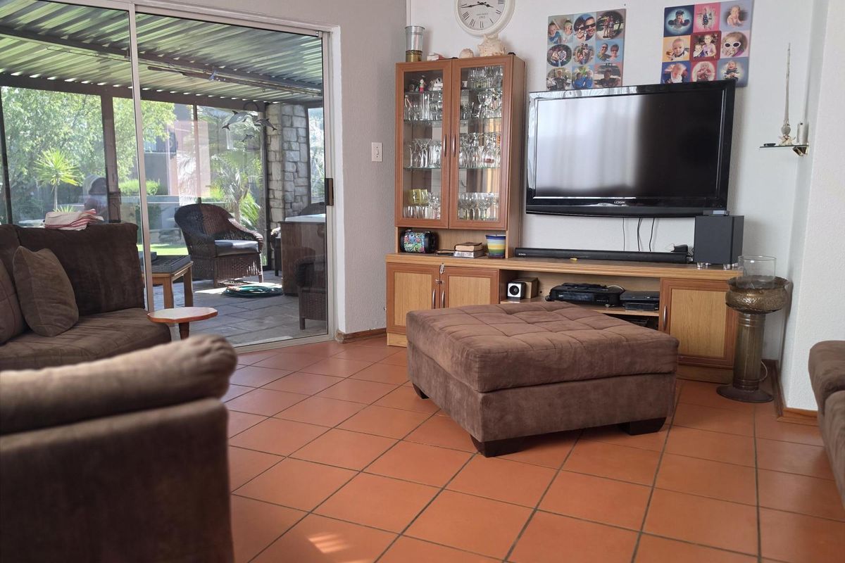 A living room featuring terracotta floor tiles and a large sliding glass door providing access to a covered patio area.