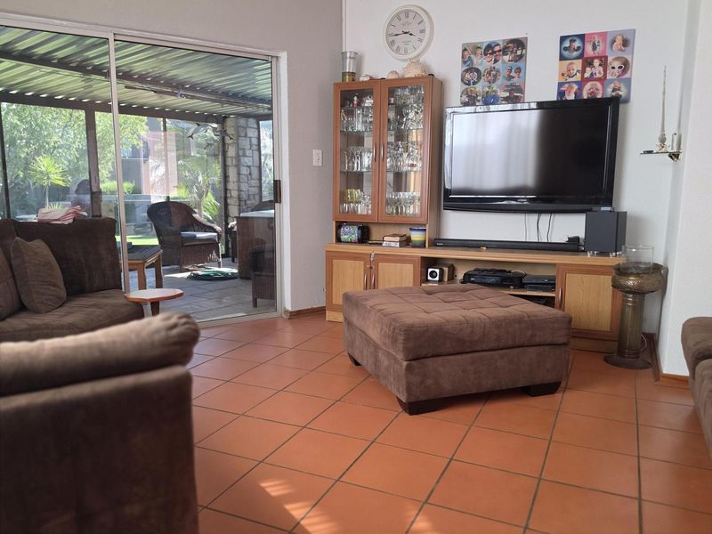A living room featuring terracotta floor tiles and a large sliding glass door providing access to a covered patio area.