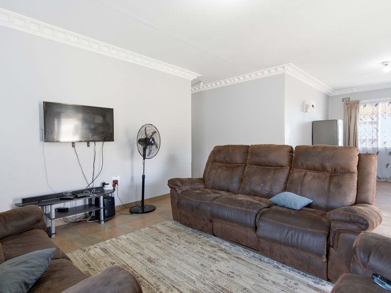 A living room featuring neutral wall paint, decorative crown molding, and tiled flooring, providing a functional and well-lit space.