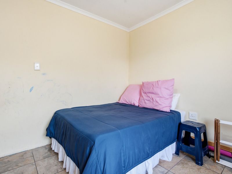 A compact bedroom featuring tiled flooring and neutral wall finishes, currently requiring minor cosmetic attention to address wall markings.
