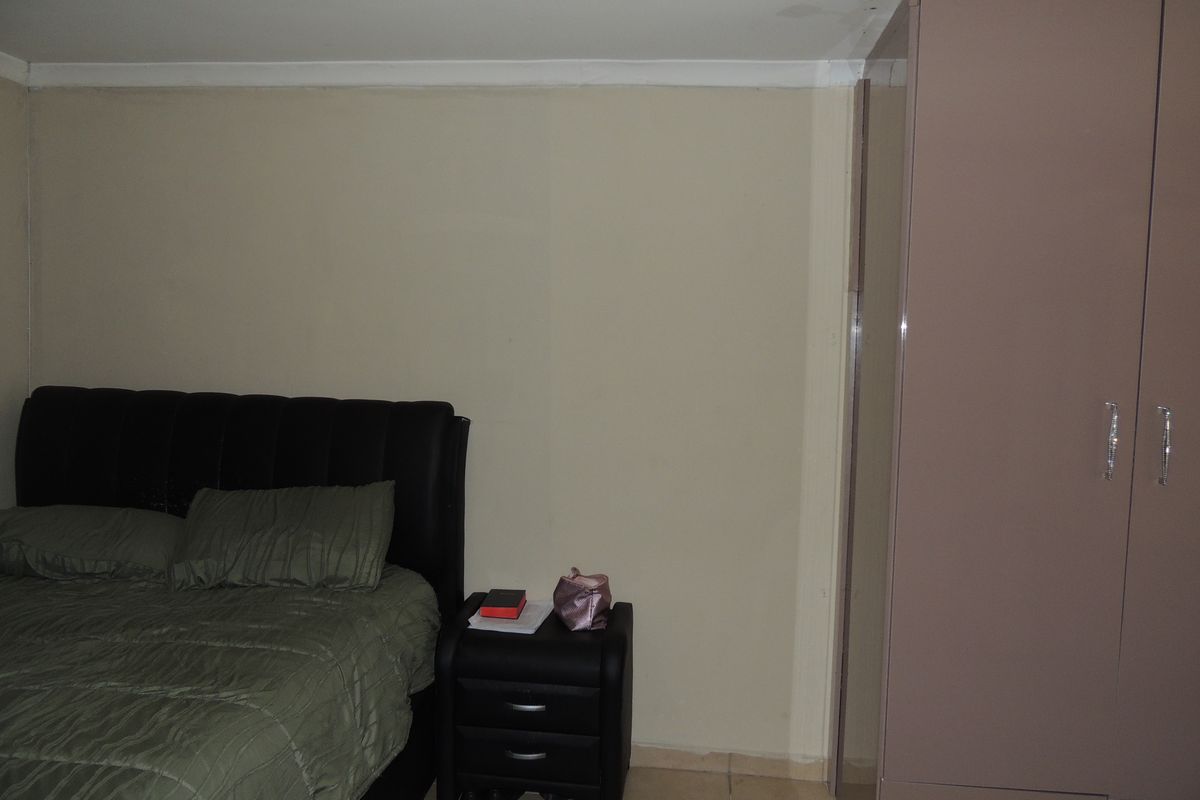 A bedroom featuring tiled flooring and a built-in wardrobe, showing visible signs of ceiling water damage requiring maintenance.