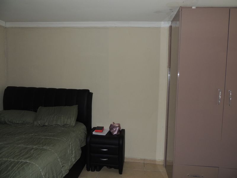 A bedroom featuring tiled flooring and a built-in wardrobe, showing visible signs of ceiling water damage requiring maintenance.