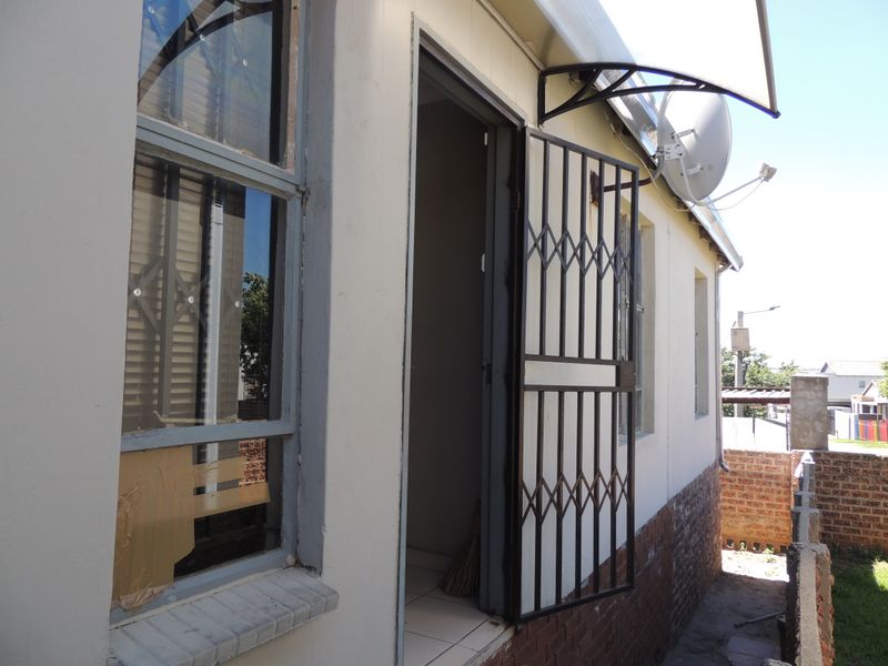 Rear exterior view of the property featuring a security gate, awning, and satellite dish installation.