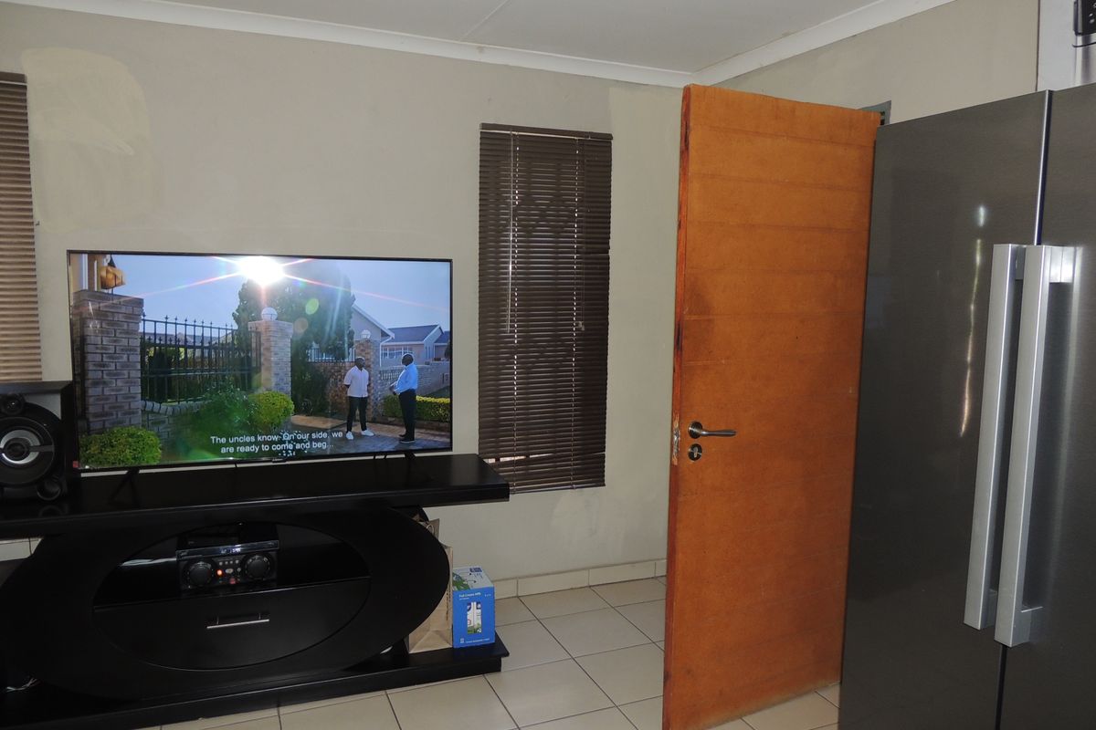 A living area featuring tiled flooring, venetian blinds, and cove cornicing, currently showing signs of wear and unfinished wall paint.