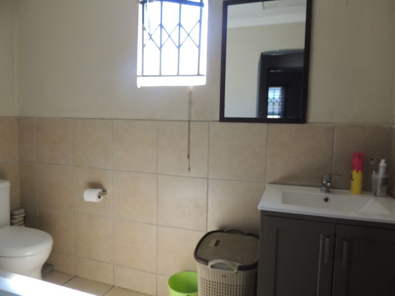 A functional bathroom featuring a vanity cabinet with a basin, a wall-mounted mirror, and tiled wall finishes.