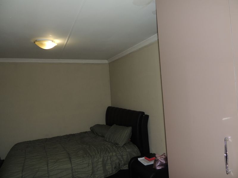 A bedroom featuring a built-in cupboard and ceiling light fixture, showing visible signs of water staining on the ceiling.