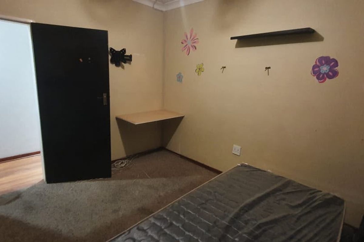 A bedroom featuring a built-in desk, floating shelf, and coving, with carpeted flooring and neutral wall paint.
