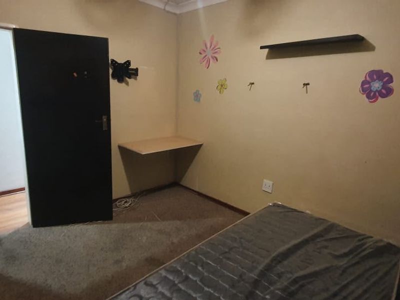 A bedroom featuring a built-in desk, floating shelf, and coving, with carpeted flooring and neutral wall paint.
