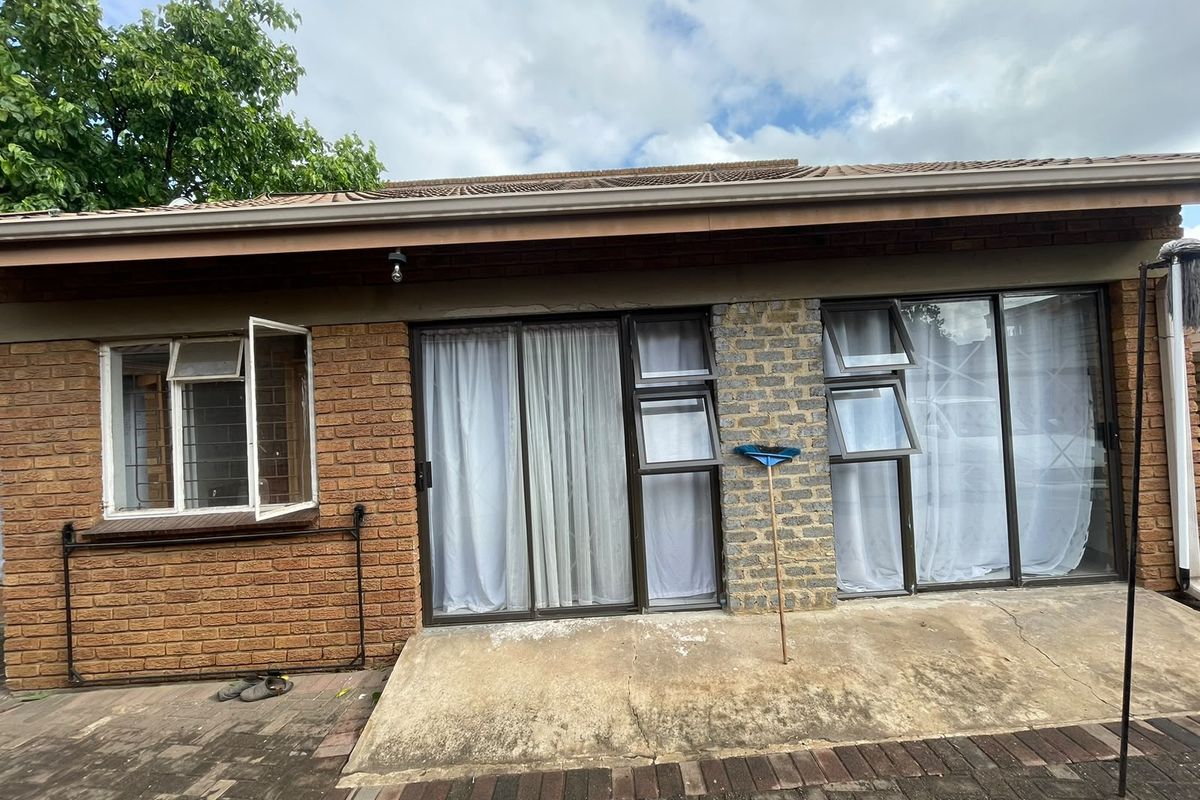 Rear exterior view of the house featuring a brick facade, sliding glass doors, and a concrete patio area.