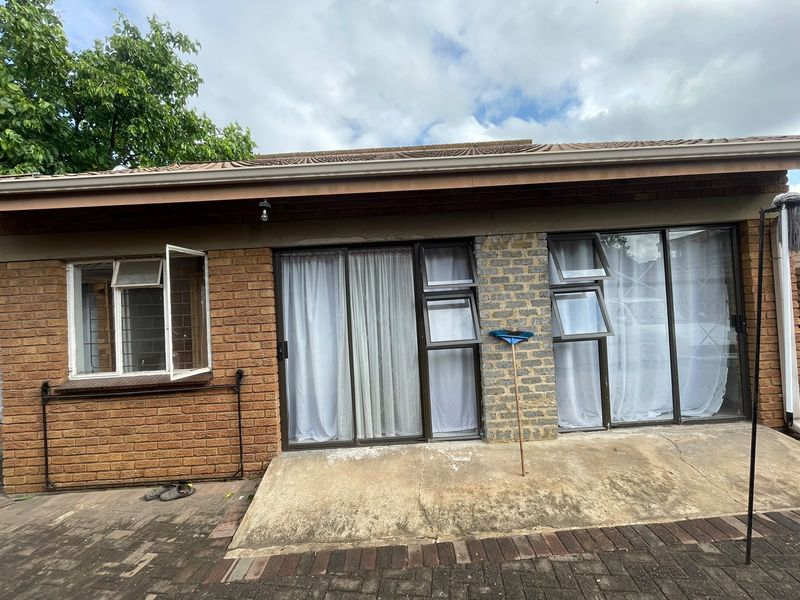 Rear exterior view of the house featuring a brick facade, sliding glass doors, and a concrete patio area.