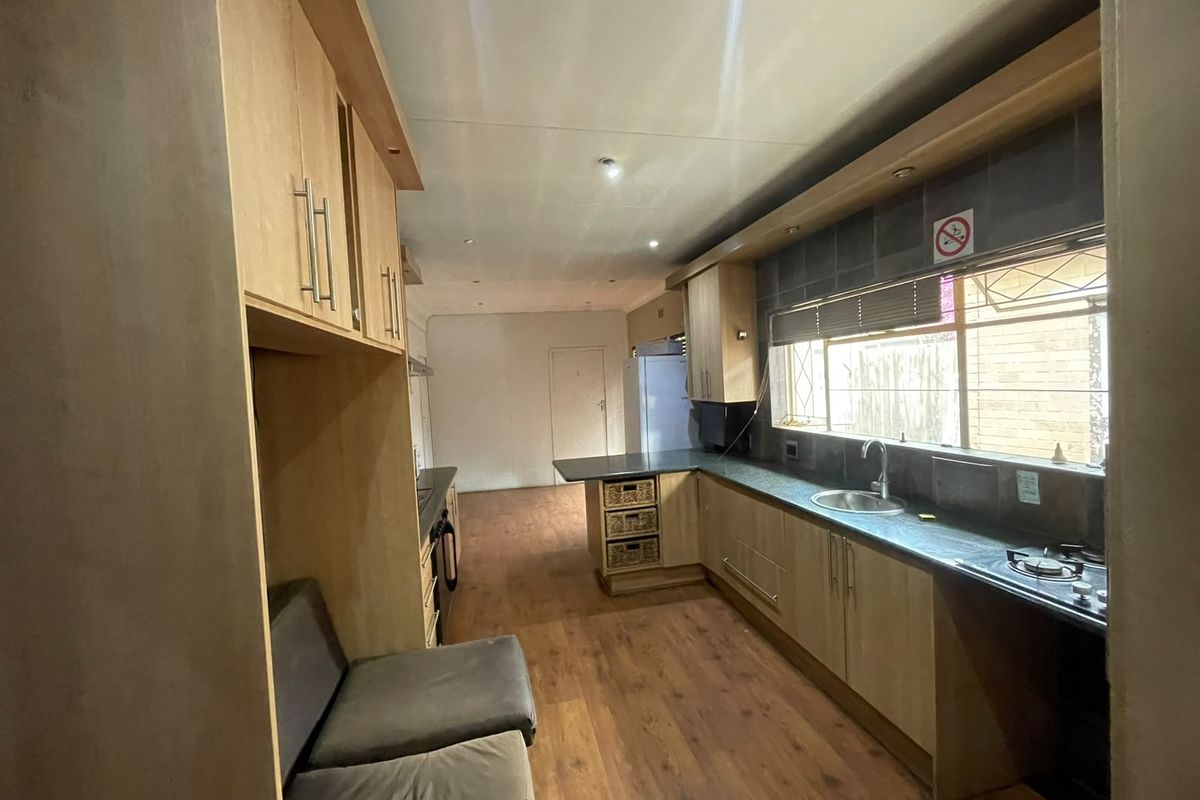 Functional kitchen featuring light wood cabinetry, laminate countertops, a gas hob, and a stainless steel sink with ample natural light.