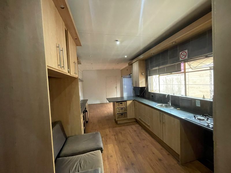 Functional kitchen featuring light wood cabinetry, laminate countertops, a gas hob, and a stainless steel sink with ample natural light.