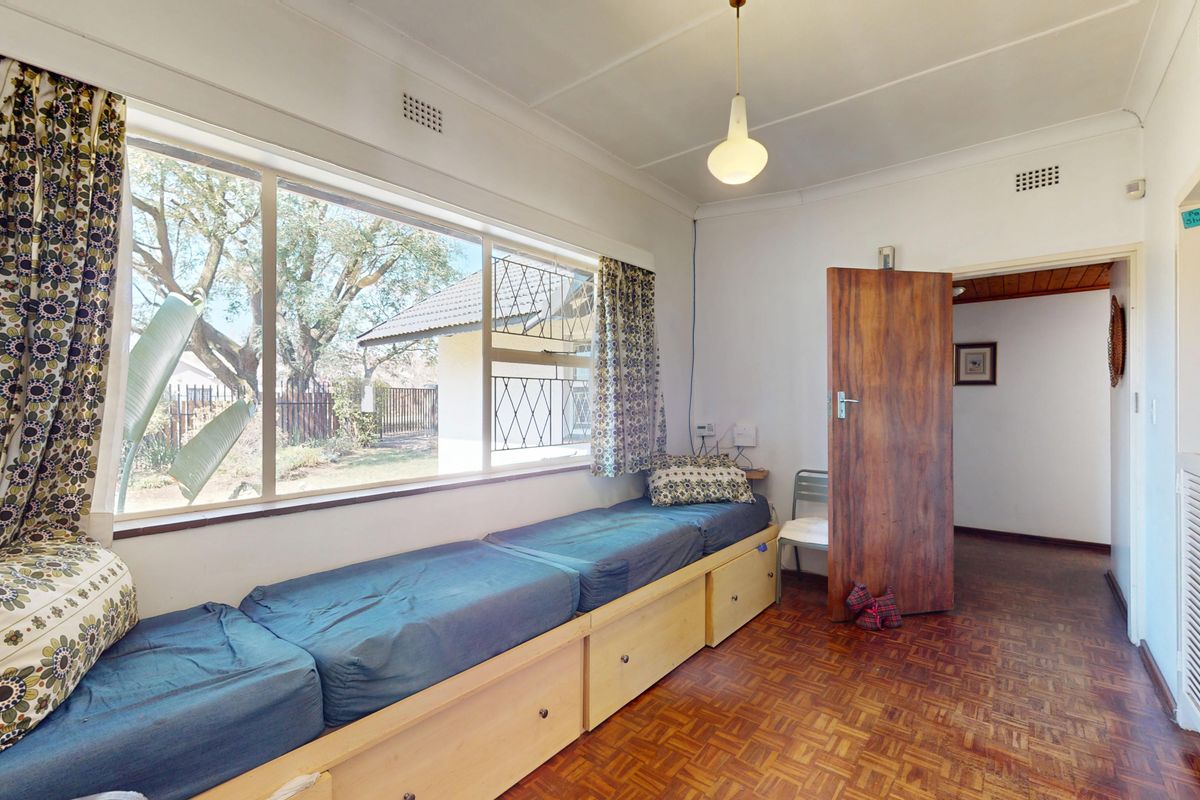 A bedroom featuring classic parquet flooring, a built-in window seat with storage, and a coved ceiling, offering a functional and well-lit living space.