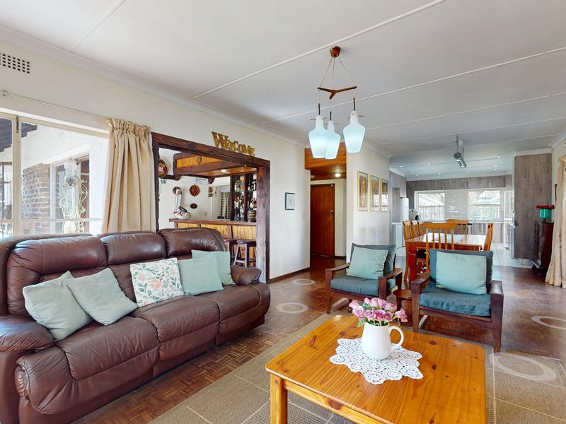 Spacious open-plan living and dining area featuring parquet flooring, a built-in bar, and large sliding doors providing access to the outdoor patio.