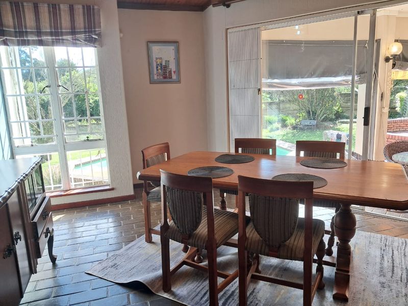 A dining room featuring tiled flooring, large windows, and sliding glass doors that provide natural light and access to the outdoor pool area.