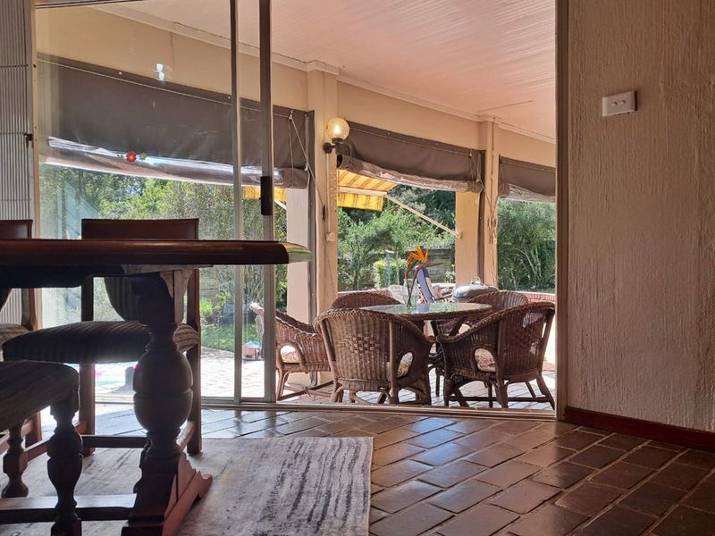 A covered outdoor patio area featuring terracotta tile flooring and sliding glass door access, providing a seamless transition to the garden space.
