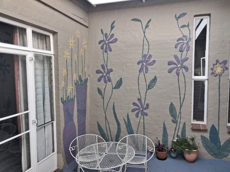 A covered patio area featuring a decorative mural on the exterior wall, providing a unique outdoor space accessible through glass doors.