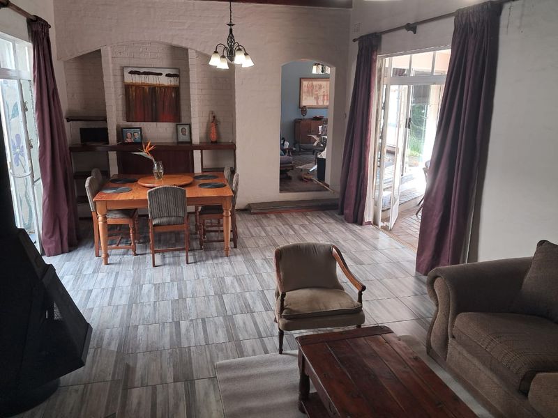 Spacious open-plan living and dining area featuring tiled flooring, an exposed brick archway, and direct access to an outdoor patio through sliding glass doors.