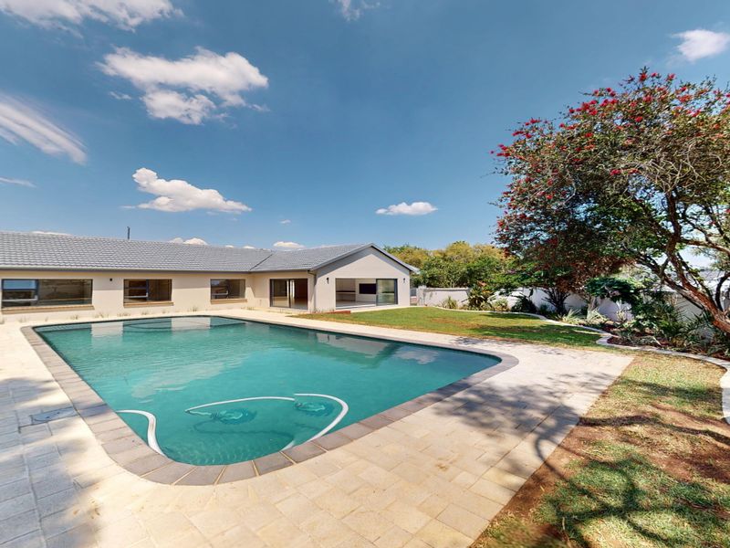 A well-maintained rear exterior featuring a swimming pool, paved pool deck, and landscaped garden area adjacent to the main house structure.