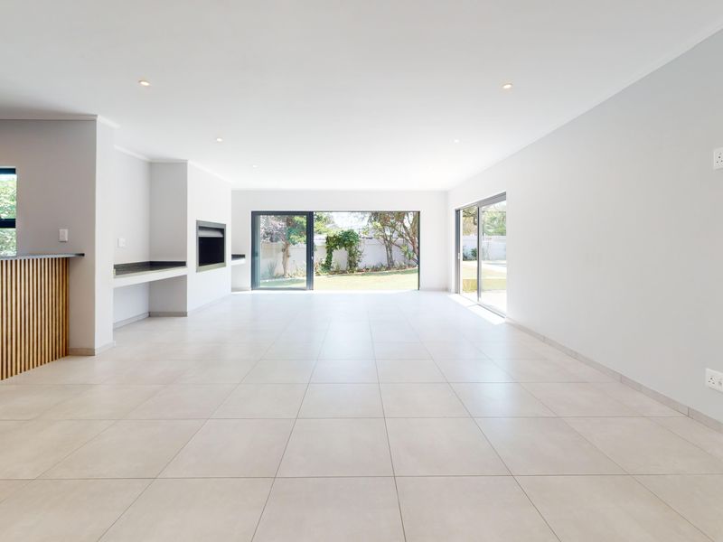 Spacious open-plan living area featuring modern tiled floors, recessed lighting, a built-in fireplace, and large sliding doors opening to the garden.