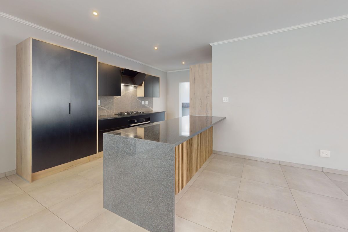Modern kitchen featuring sleek black cabinetry, stone countertops, a central island with timber detailing, and integrated appliances in a clean, open-plan space.
