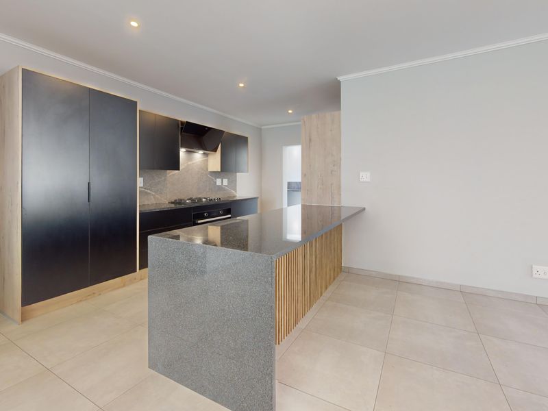 Modern kitchen featuring sleek black cabinetry, stone countertops, a central island with timber detailing, and integrated appliances in a clean, open-plan space.