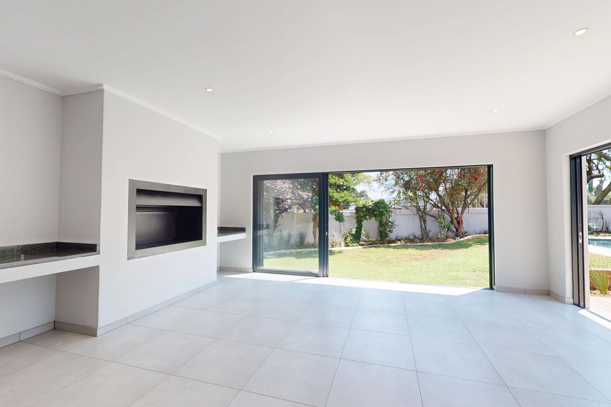 Spacious, light-filled living area featuring a built-in fireplace, stone counter, and large sliding doors opening onto a landscaped garden and pool area.