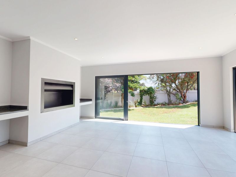 Spacious, light-filled living area featuring a built-in fireplace, stone counter, and large sliding doors opening onto a landscaped garden and pool area.