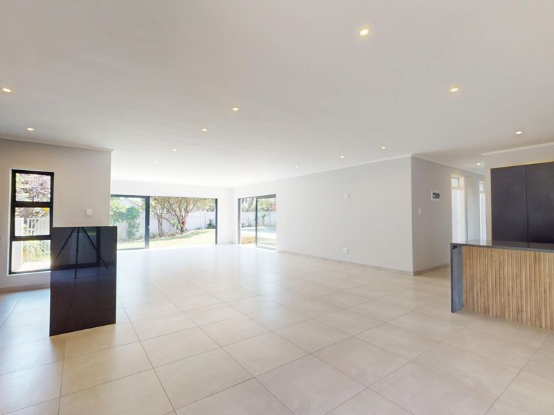 Spacious open-plan living and kitchen area featuring modern cabinetry, stone countertops, large sliding glass doors, and neutral tiled flooring throughout.