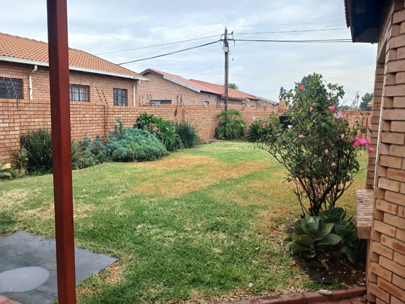 A private rear garden featuring a lawn area enclosed by brick boundary walls with integrated electric fencing.