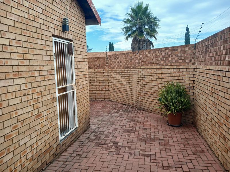 A private rear courtyard featuring face brick walls, paved flooring, and a secure entrance gate with electric fencing.