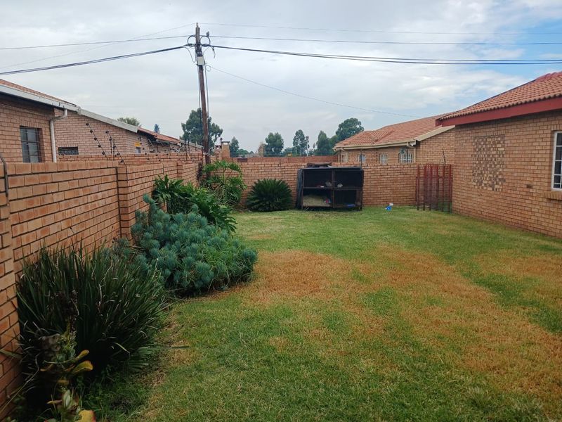 A private rear garden featuring a lawn area enclosed by brick boundary walls with integrated electric fencing.